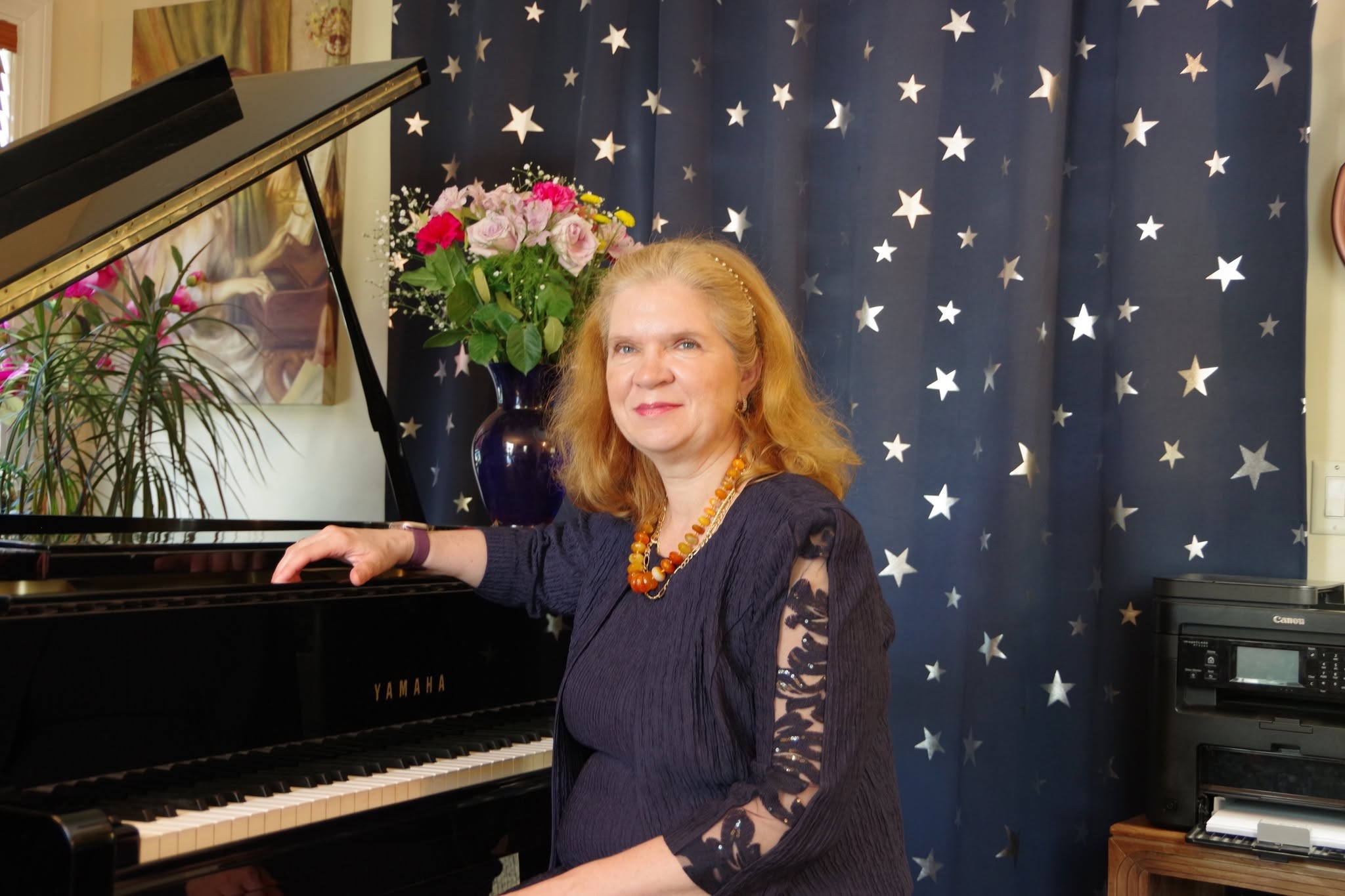 Dr. Olga Berkovich seated beside a piano
