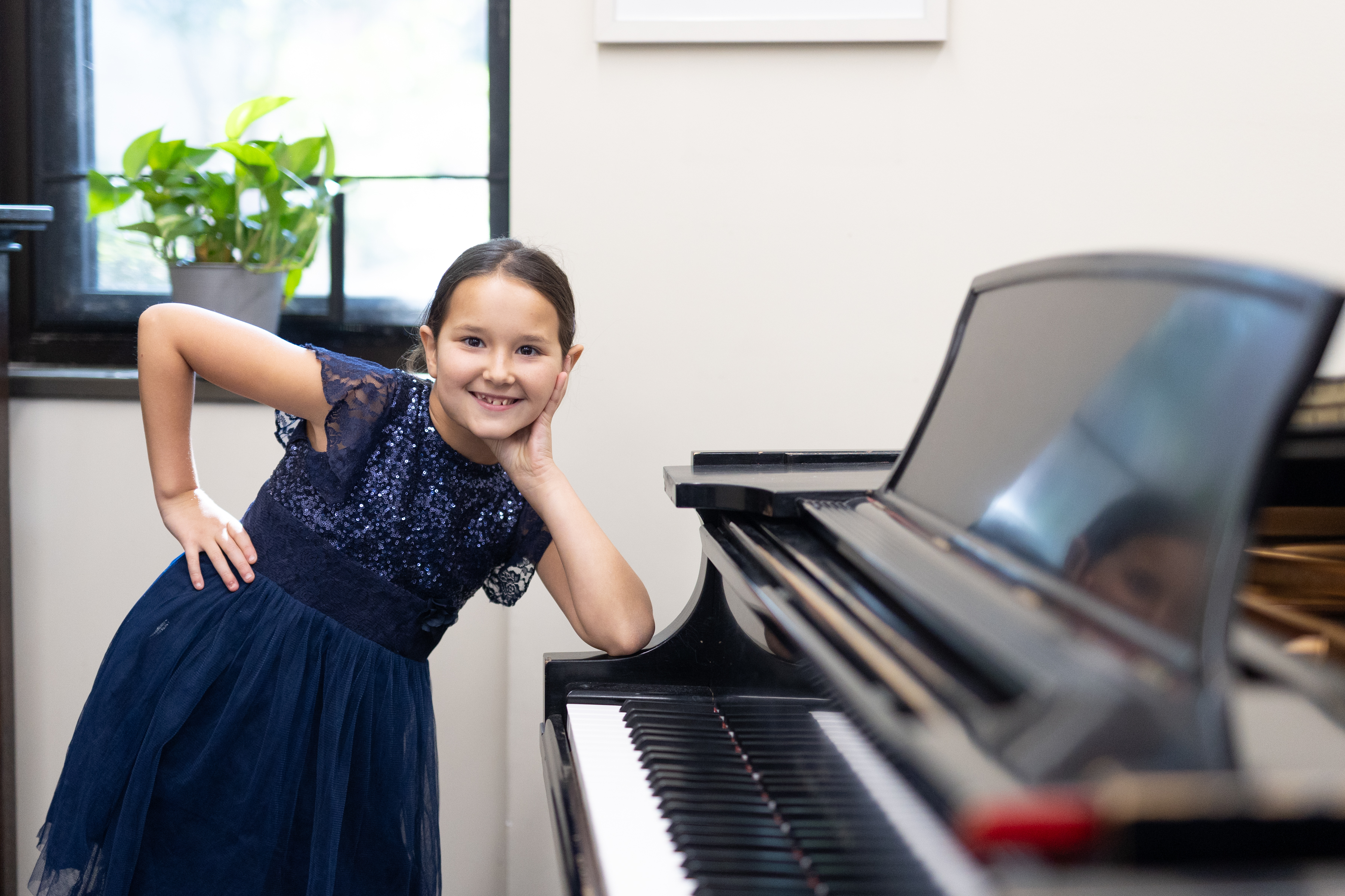 Young pianist Isabella beside a piano